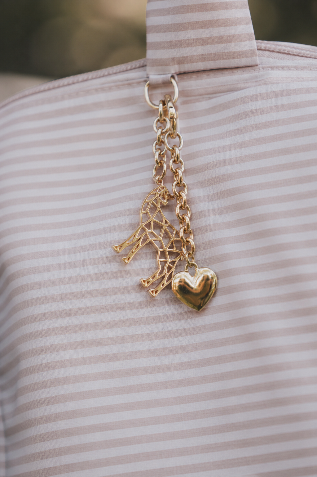 Lily Keychain met hartje als bedel, hangend aan een roze luiertas