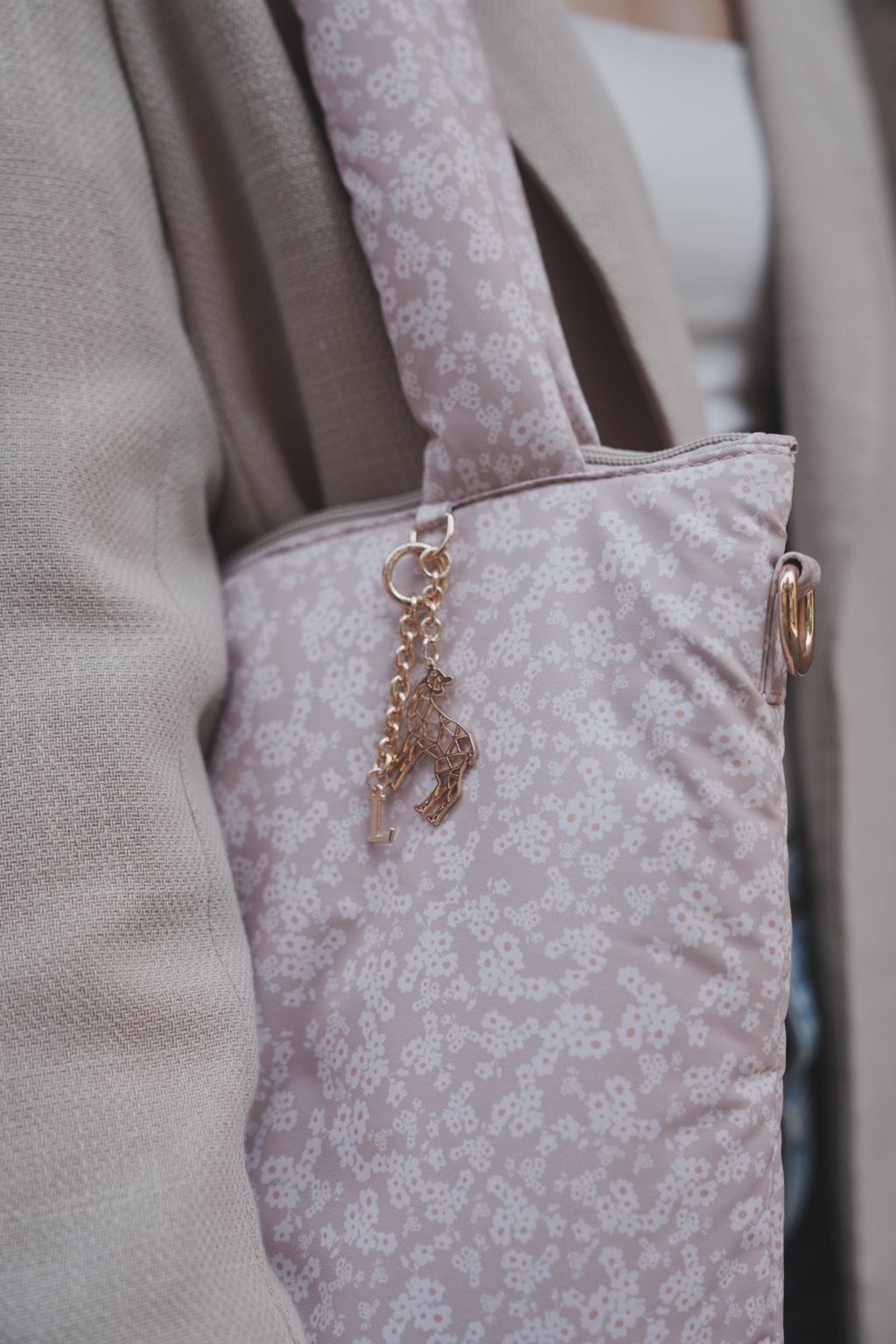 Close-up van de Lily Keychain met initiaal aan de zijkant van een lila tas met bloemenprint