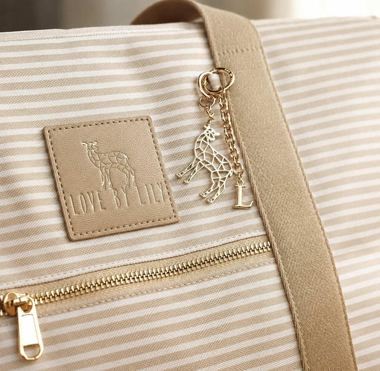 Gouden sleutelhanger met initiaal aan de rits van een crèmekleurige Love by Lily tas