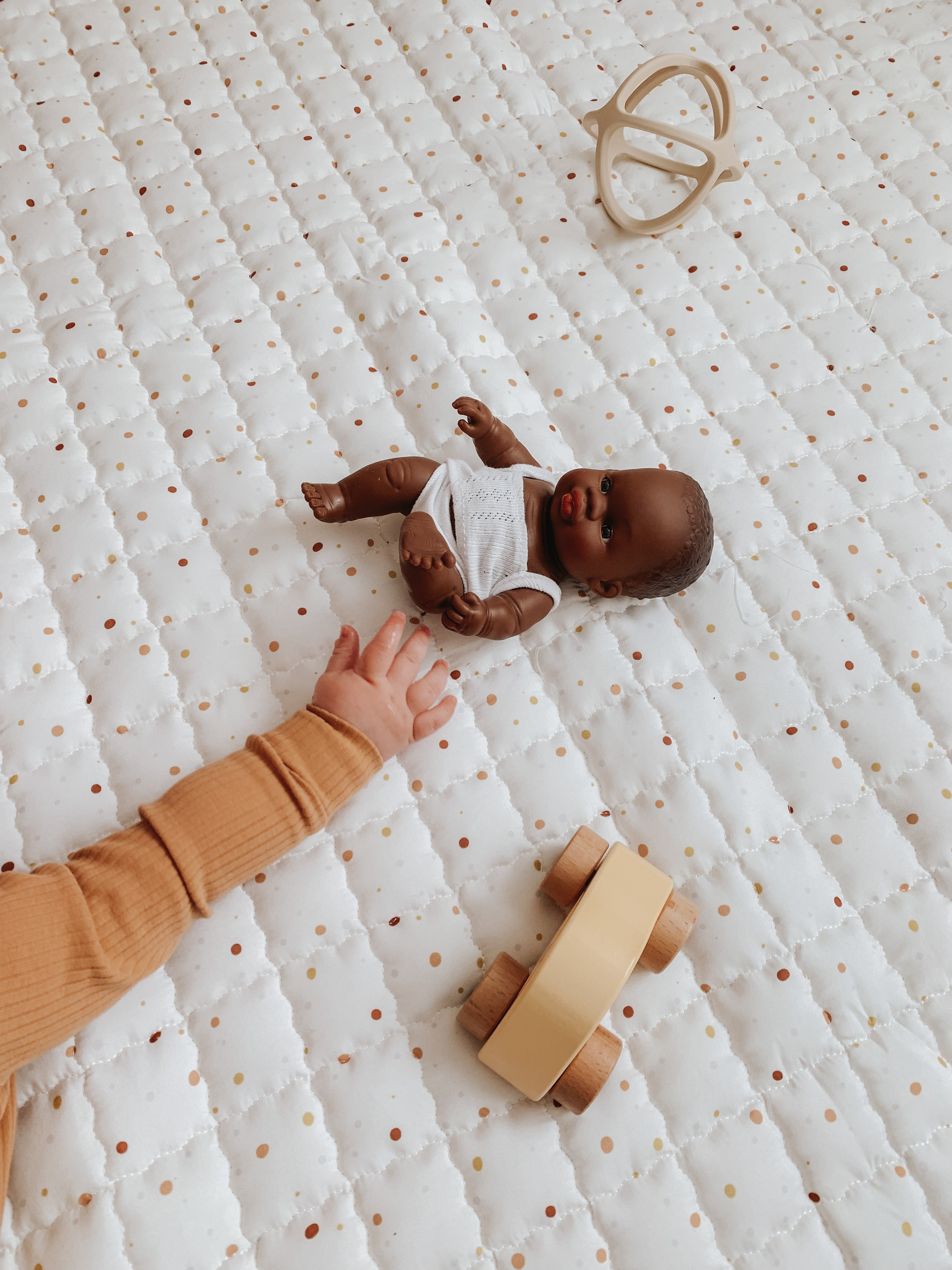 Baby op rond Goldmine speelkleed met speelgoed in een rustige setting.