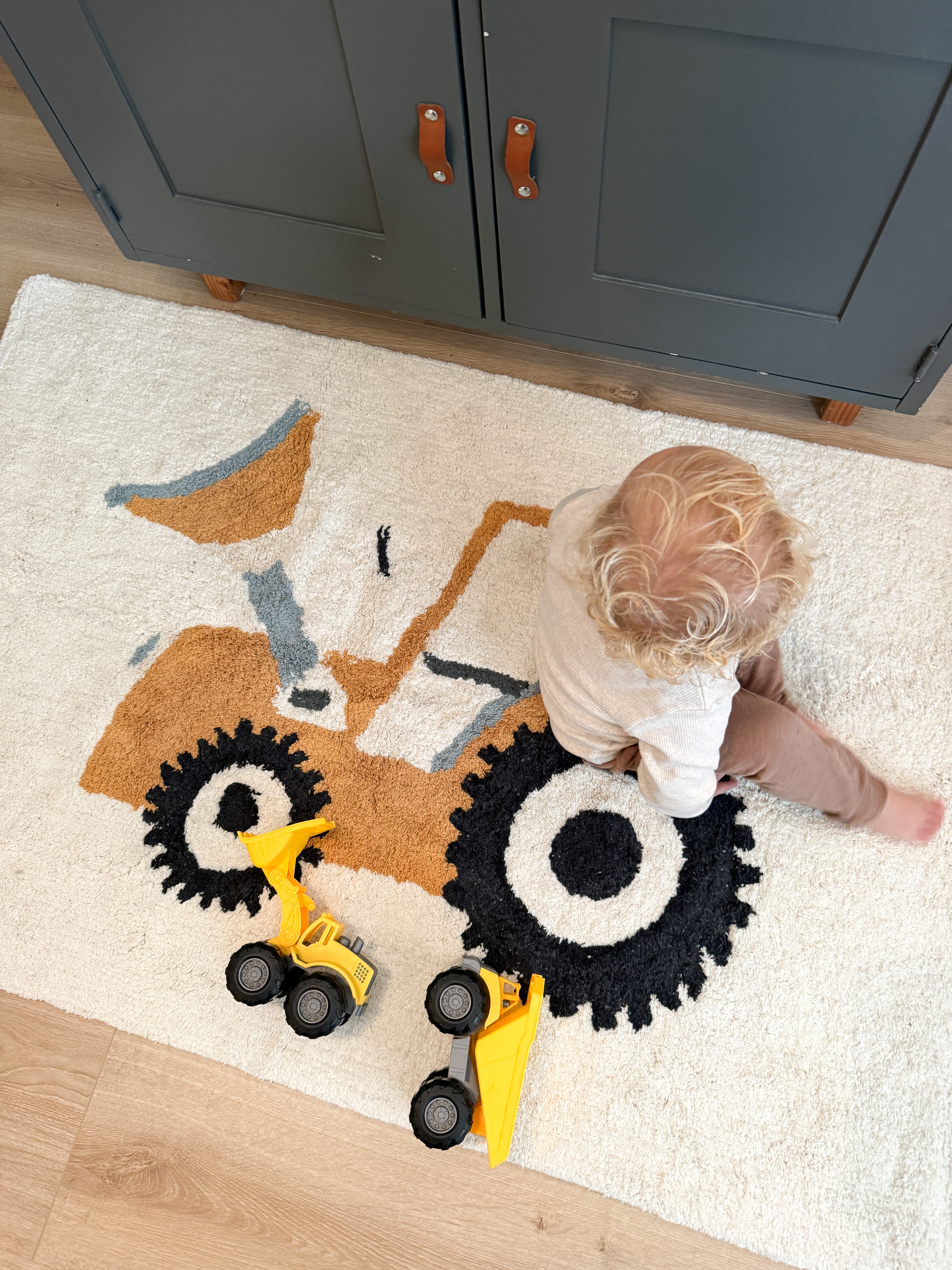 Babykamer vloerkleed met een zachte beige achtergrond en tractor print