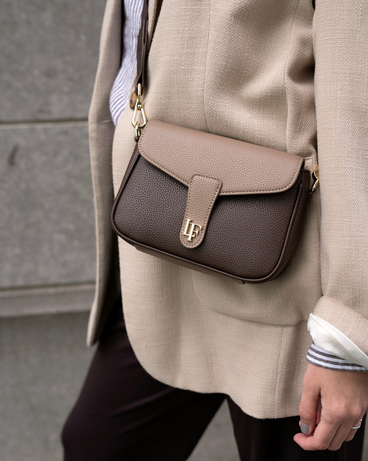 Vrouw in beige blazer loopt door Rotterdam met een bruine leren Femme crossbodytas