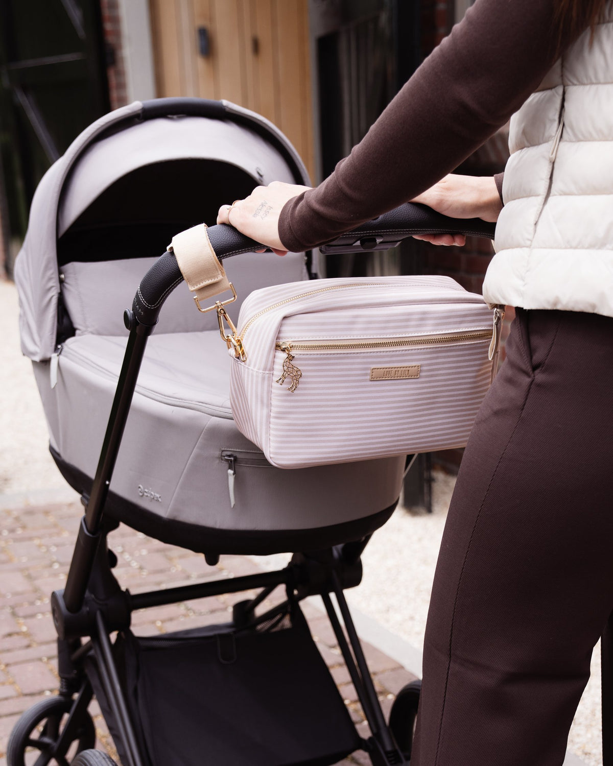 Vrouw duwt een kinderwagen met een gestreepte Love by Lily Pocket aan het duwstuk