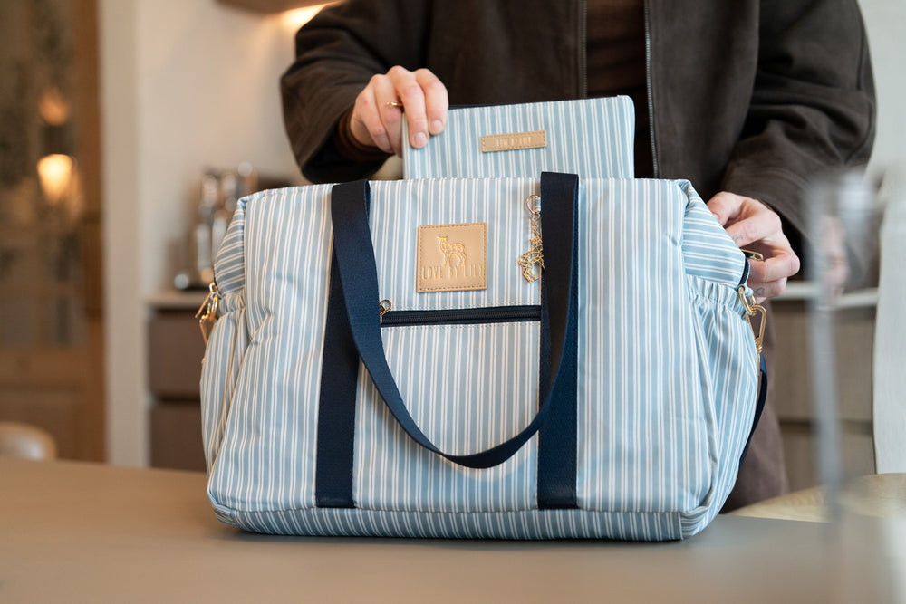 The Lily Daily Salty Sailor – blauw-wit gestreepte luiertas op het aanrecht, het bijpassende verschoningsmatje wordt in de tas gestoken