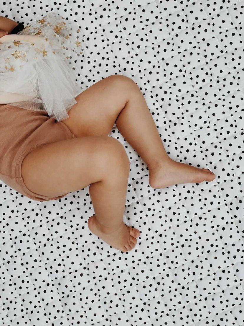 Minimalistisch speelkleed met fijne zwarte stippen – perfect voor rustige speelmomenten.