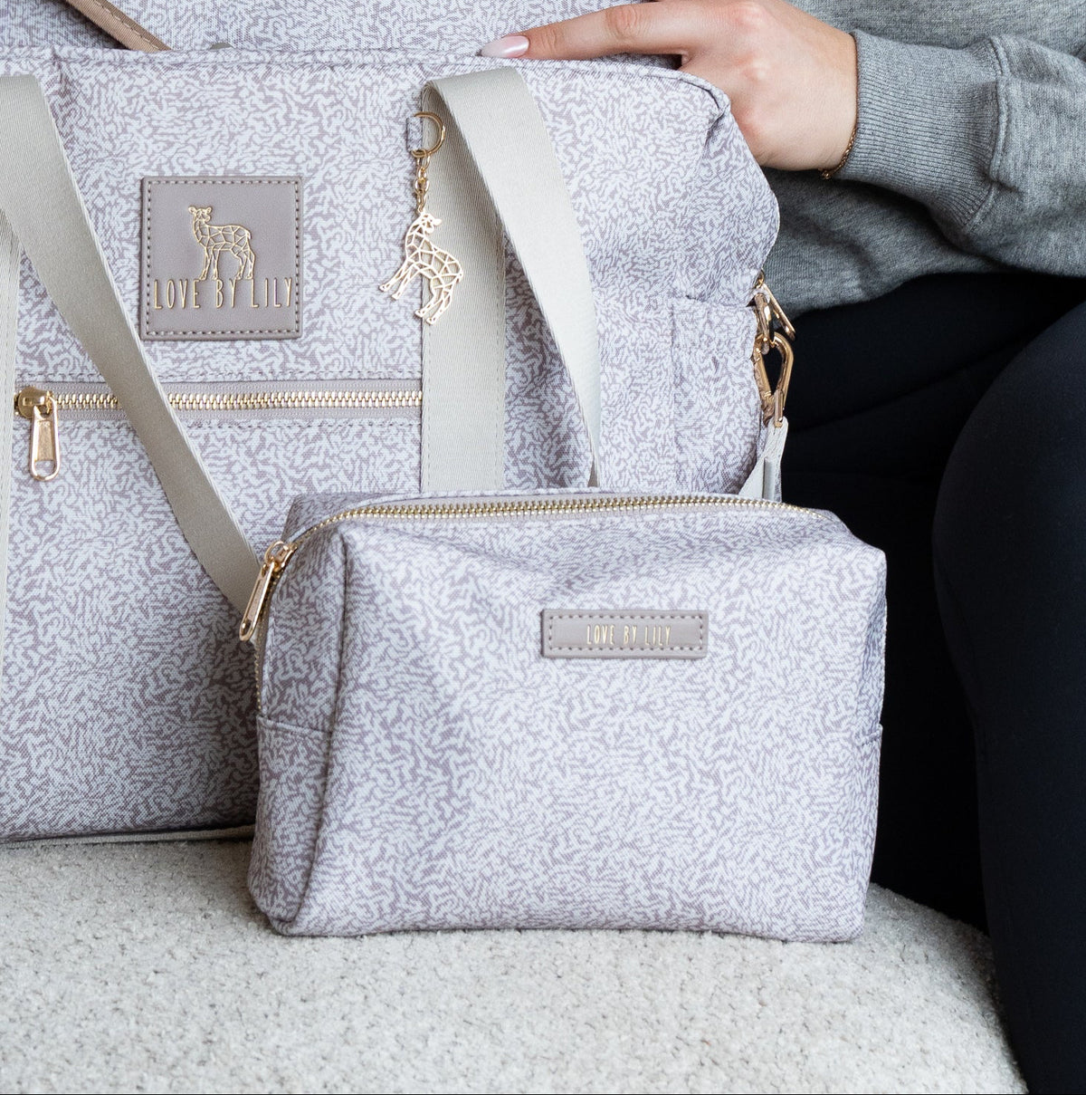 The Lily Daily Pebble Path – vrouw met verschoningsmatje, luiertas en toilettasje in gespikkelde print op de bank