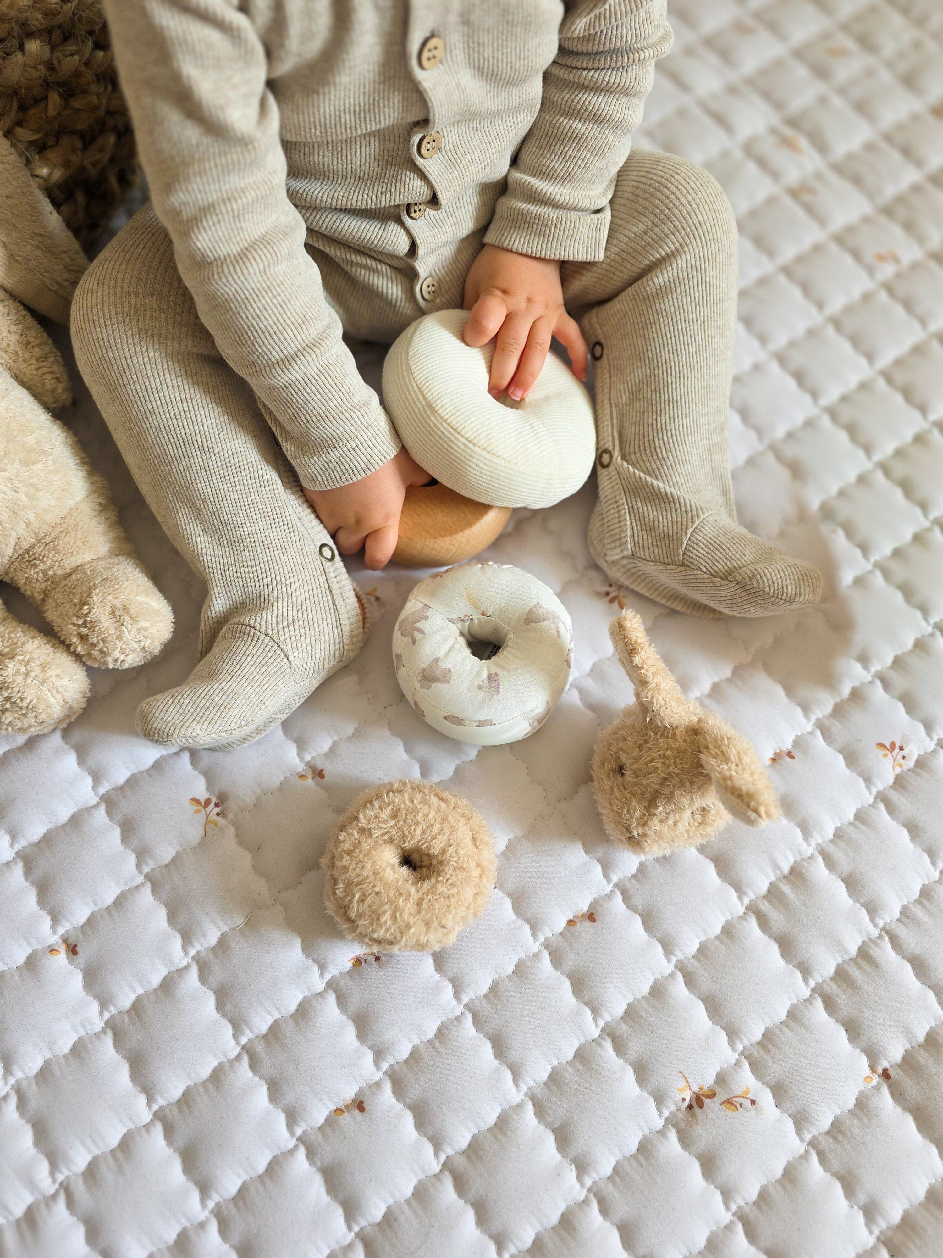 Baby zit op een rond Love by Lily Spring speelkleed met zachte print.