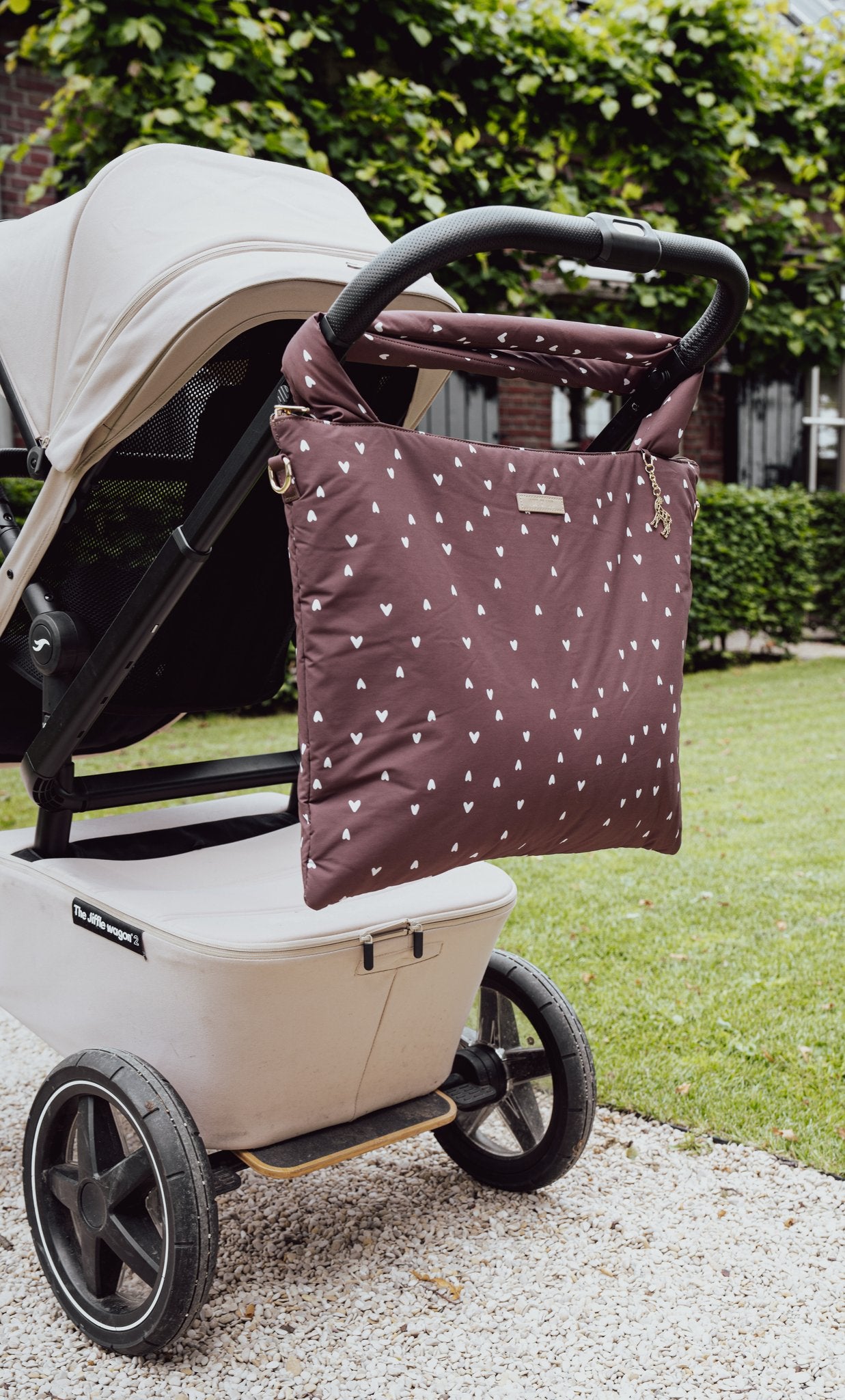 The Lily Tote luiertas van Love by Lily in Deep Amour hartjesprint, close-up hangend aan het handvat van de kinderwagen